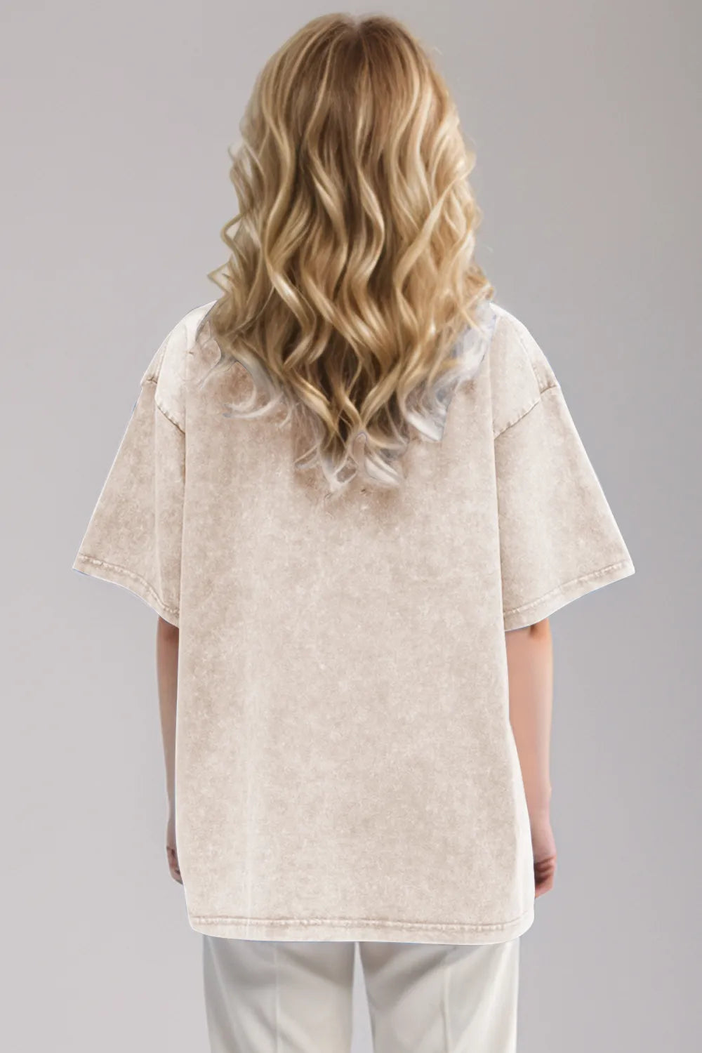 Person wearing a beige oversized shirt and pants set on a gray background