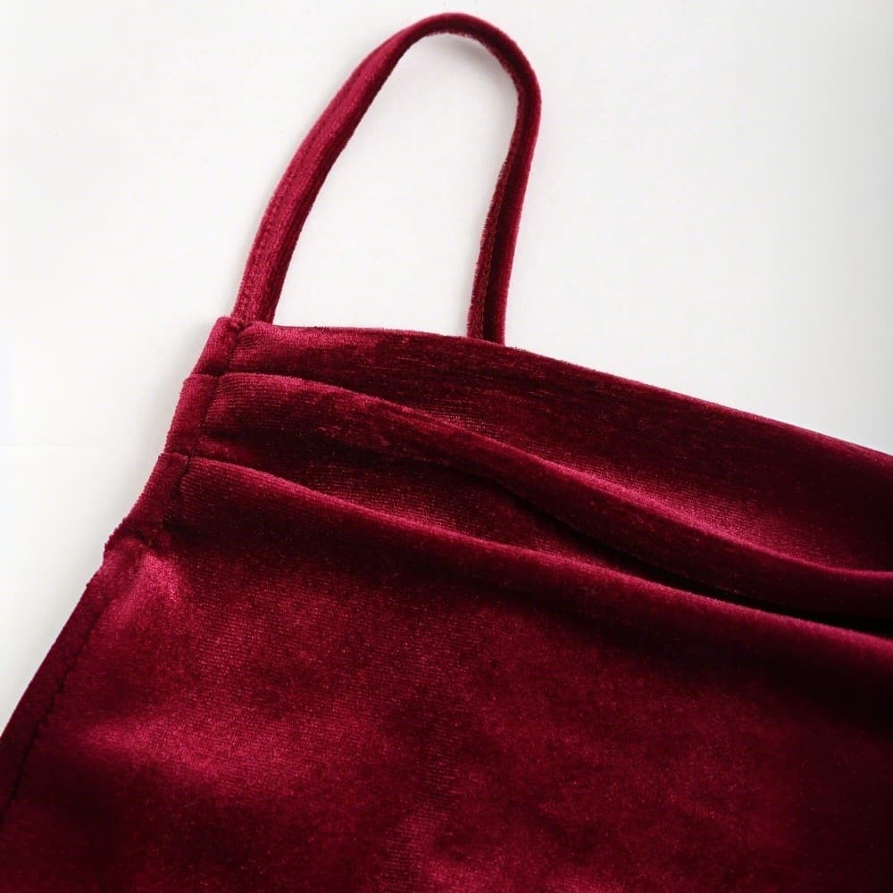 Close-up of a burgundy velvet garment with straps on a light gray background