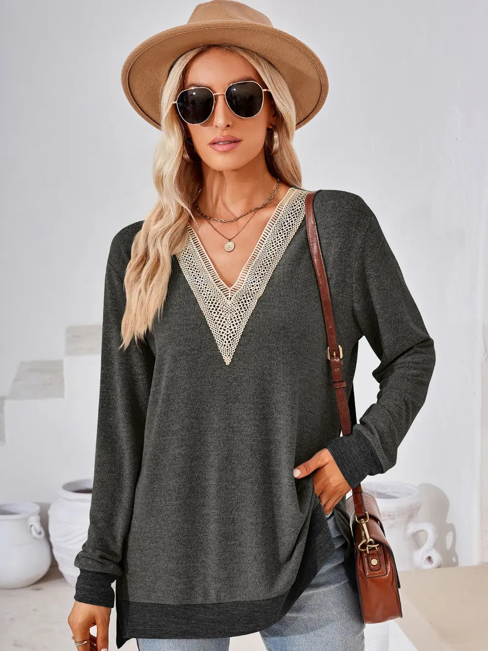 Woman wearing a dark gray sweater with lace details, sunglasses, and a beige hat indoors.