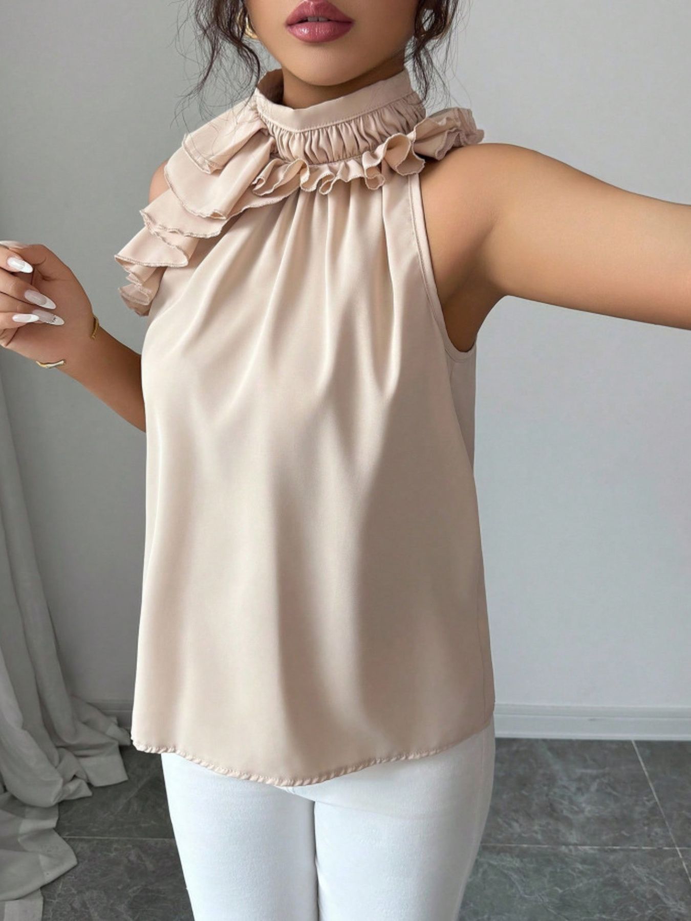 Cream ruffle high neck sleeveless button top styled with white straight-leg Trouser