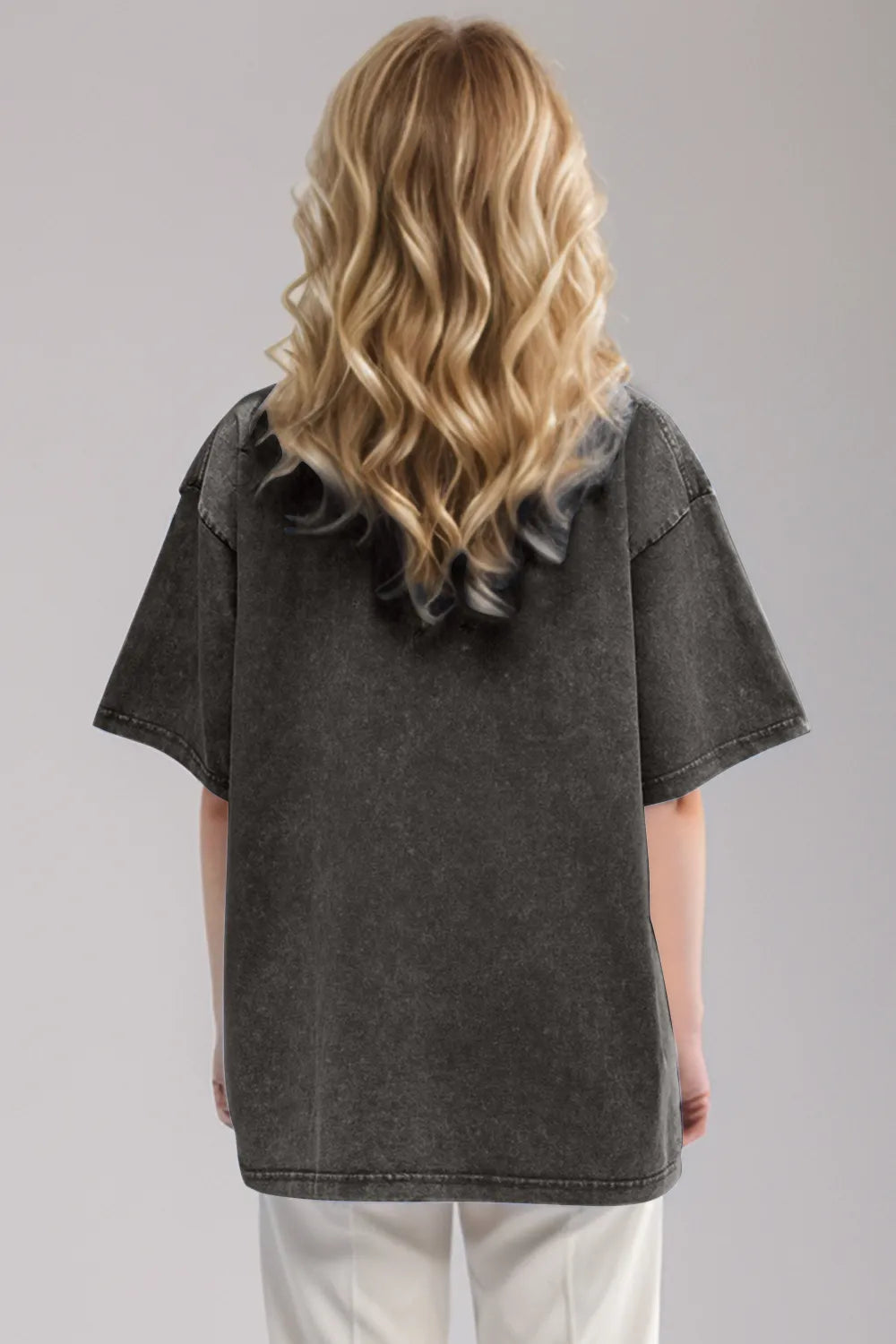 Person wearing a black denim shirt with ruffled sleeves on a gray background