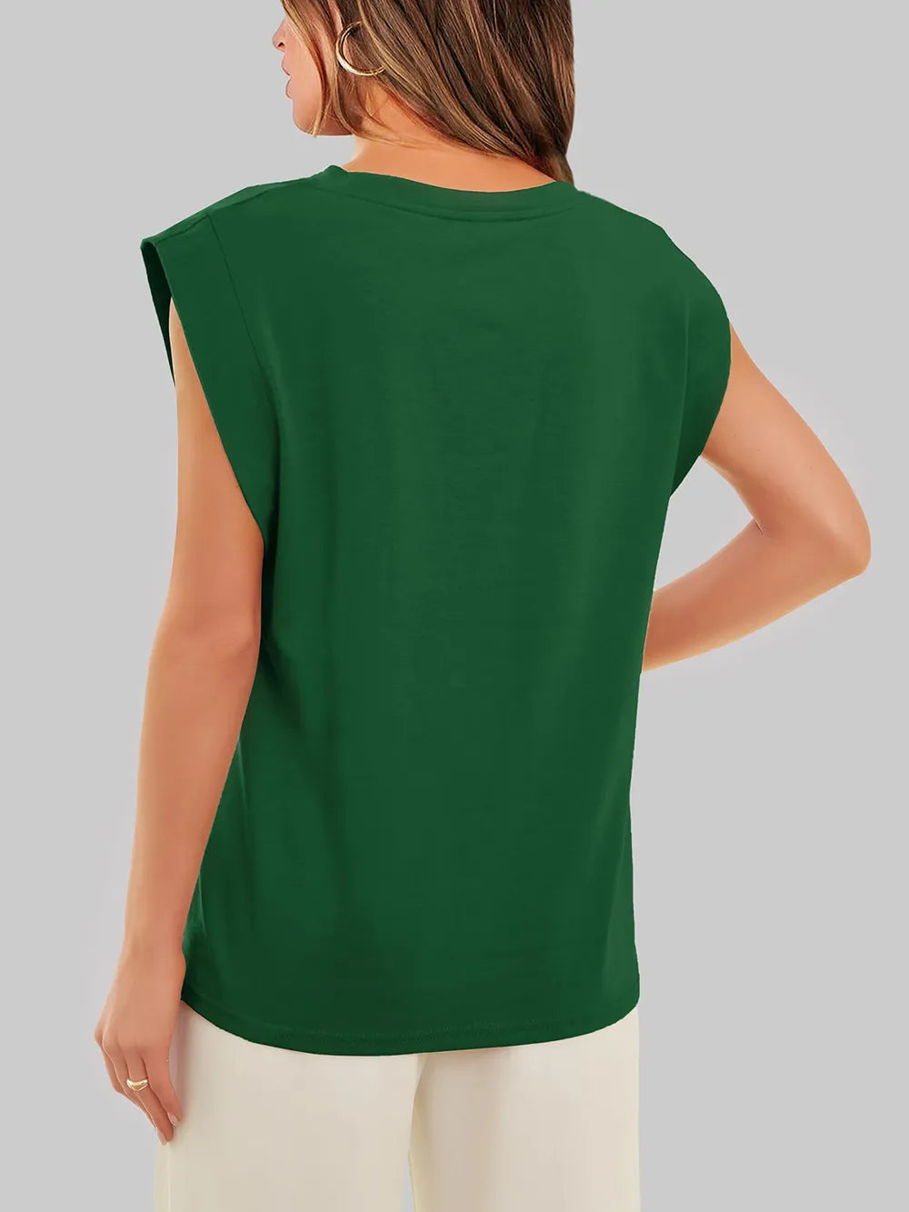 Person wearing a green sleeveless top on a plain background