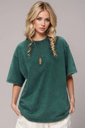 Woman wearing a green oversized t-shirt against a plain background
