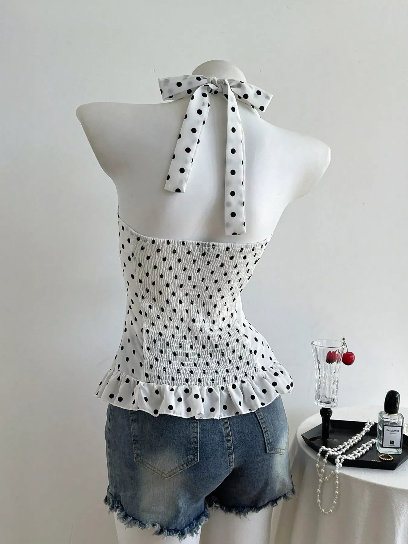 Polka dot top on a mannequin with denim shorts, white background
