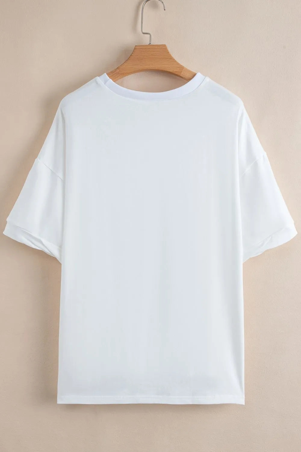 White t-shirt on a wooden hanger against a beige background