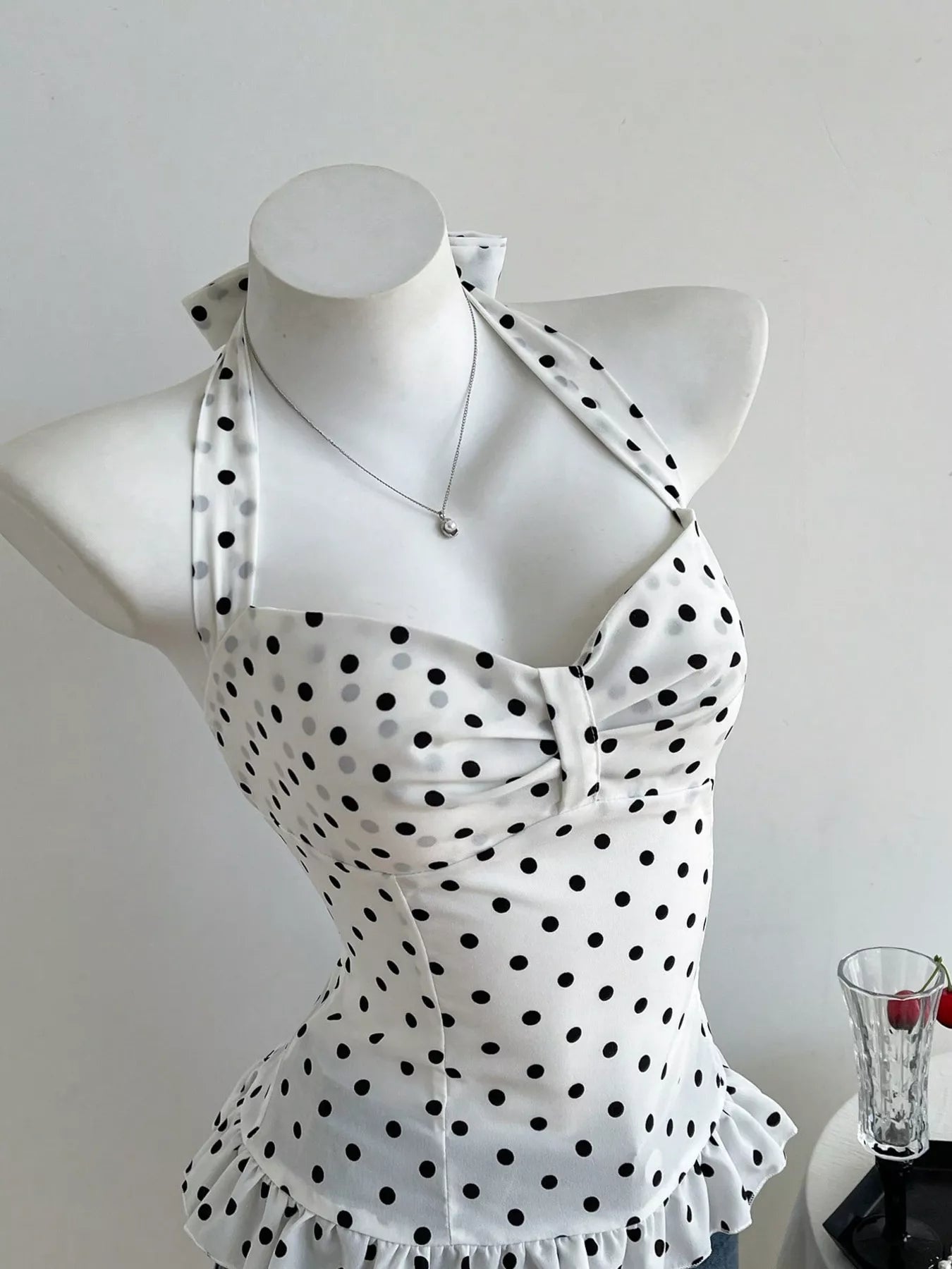 White swimsuit with black polka dots on a mannequin against a white background