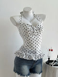 White top with black polka dots on a mannequin against a white background