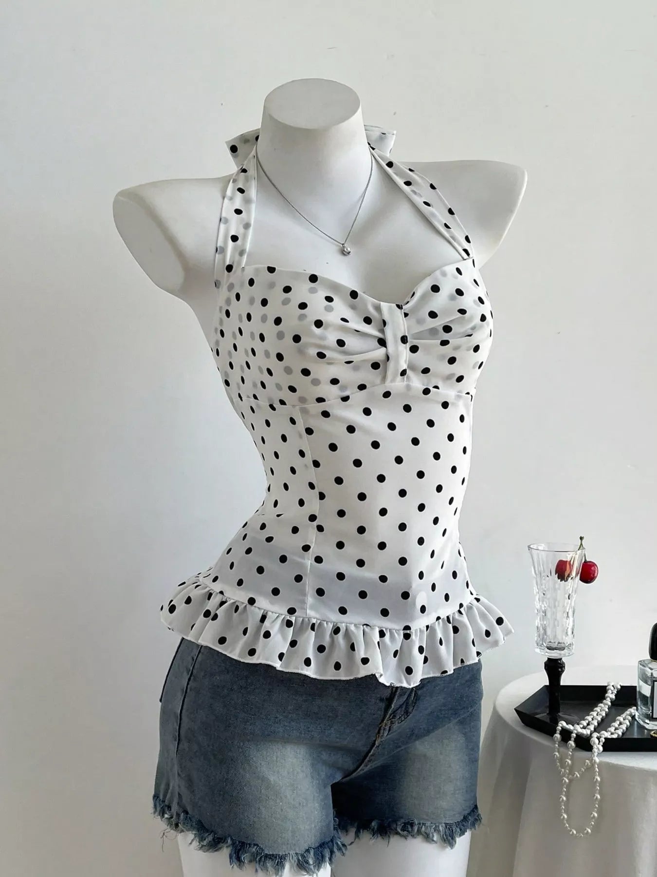 White top with black polka dots on a mannequin against a white background