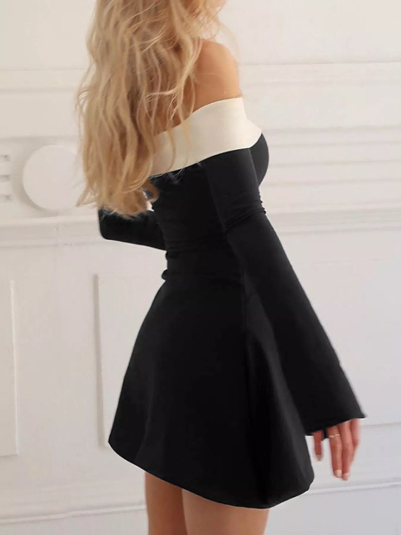 black-a-line-mini-dress-party-heels
Party-ready styling: black off-shoulder long sleeve mini dress with strappy heels and clutch
Black and white dress worn by a person with blonde hair against a white background