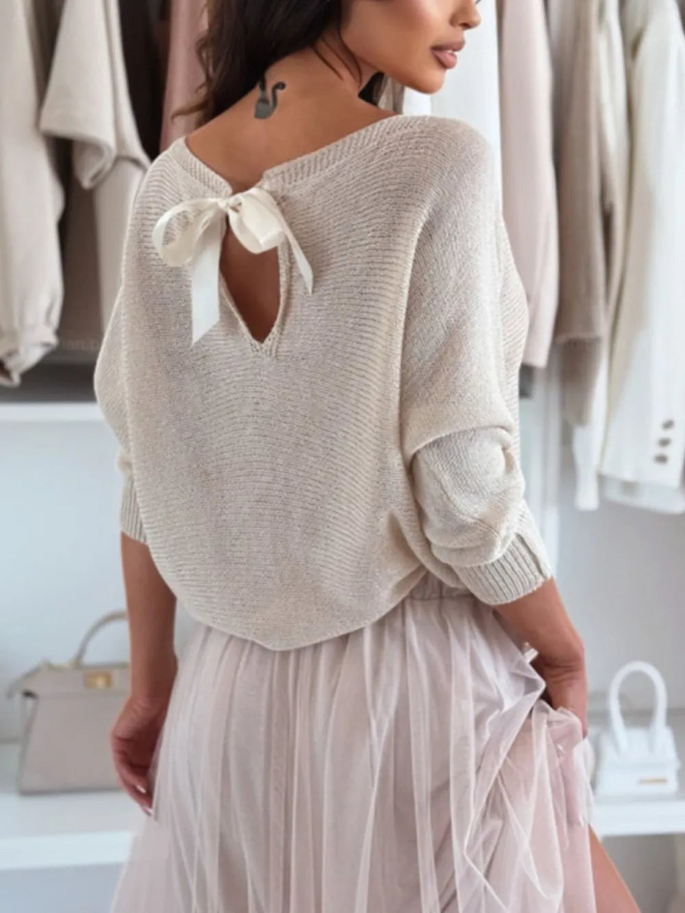 Party-ready styling of bow back off-shoulder sweater with leather skirt

Woman wearing a light gray sweater with a bow detail and a sheer skirt in a clothing store.