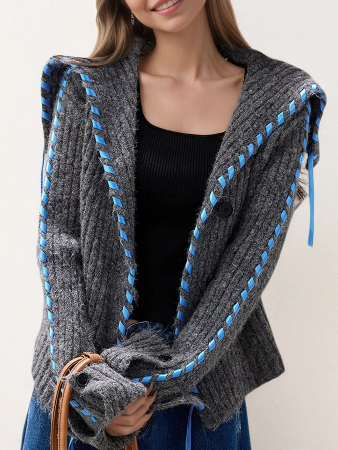 Close-up of soft cable knit texture and contrast stitching on cream cardigan