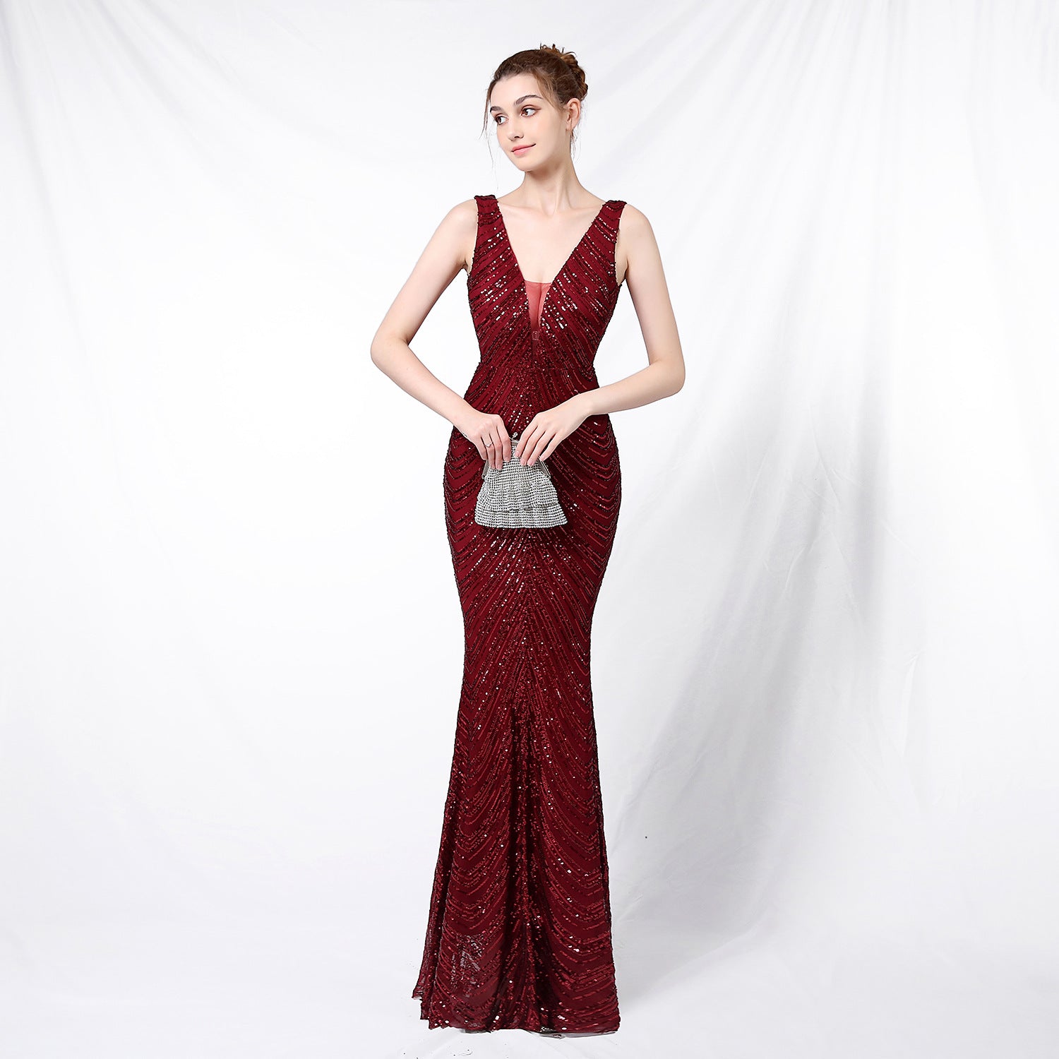 celeste-sequin-gown-red-carpet-pose
Red-carpet glamour shot of Celeste beaded sleeveless V-neck evening gown with dramatic lighting and pose

Woman wearing a burgundy evening gown on a white background