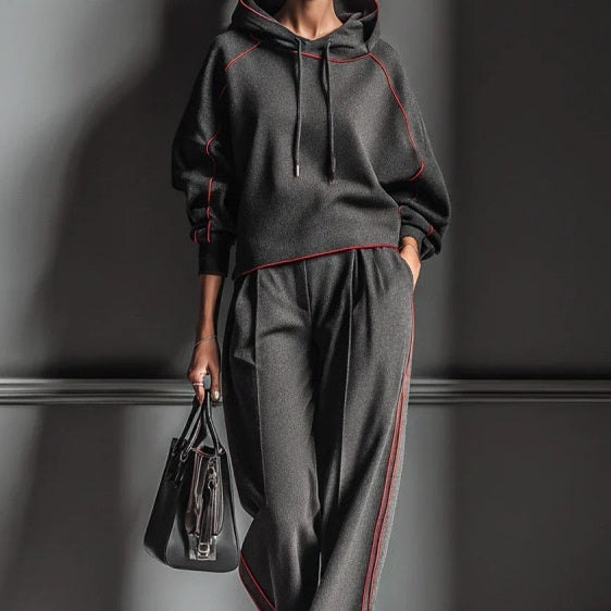 dark-grey-color-block-hoodie-tracksuit-set-full
Dark grey color block hoodie tracksuit set for women, stylish streetwear jogger outfit – OpusVenustas
Person wearing a dark gray tracksuit with red accents, holding a black handbag against a dark background.