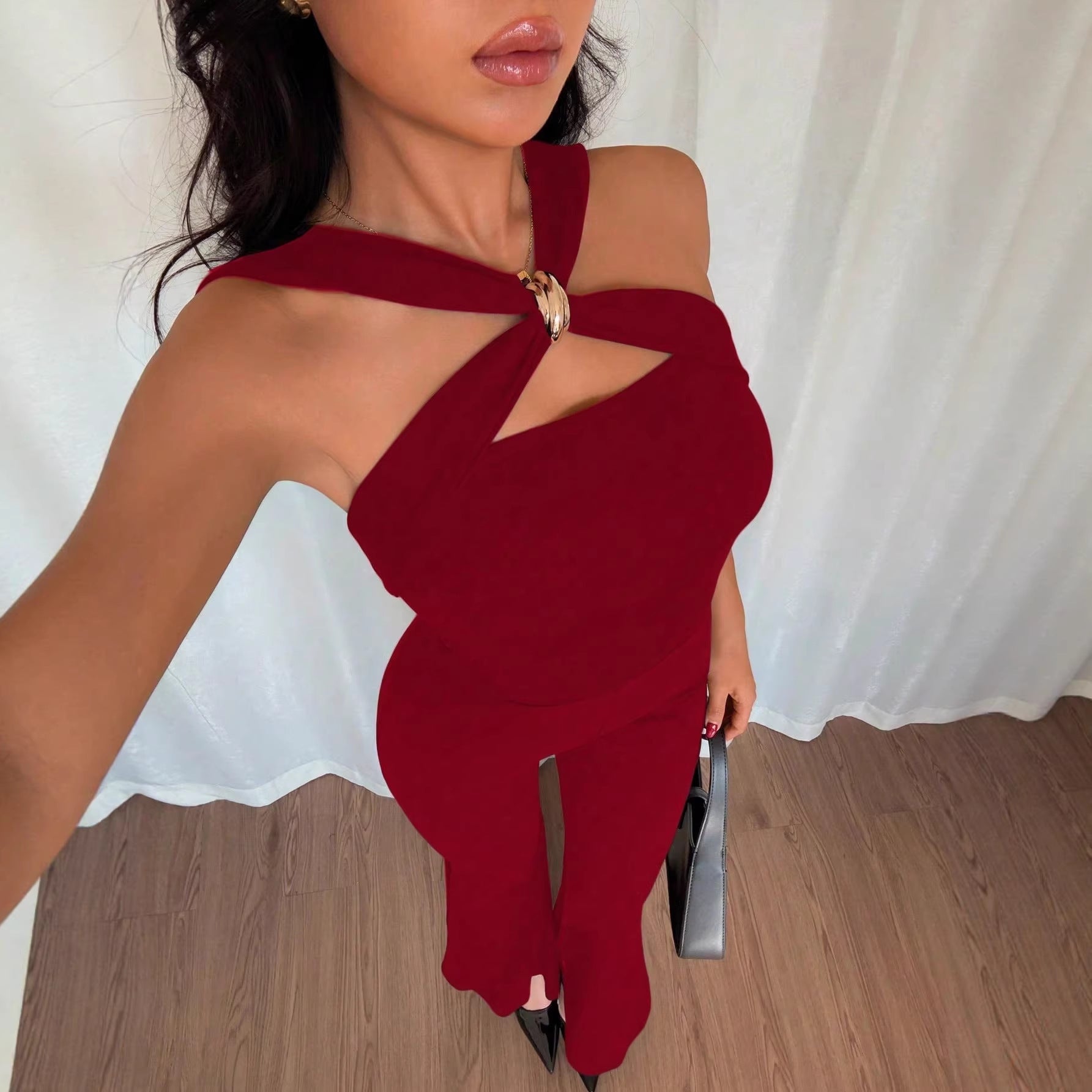 halter-flared-jumpsuit-back-view-burgundy
Back view of rich burgundy halter neck jumpsuit showing open back and flared cropped legs

Woman wearing a red outfit with cut-out design against a white curtain background