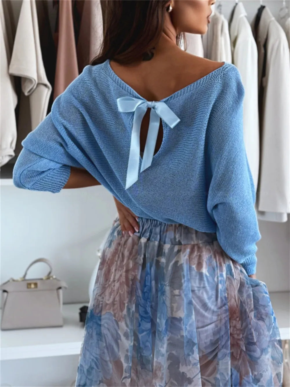  Soft lightweight knit texture close-up on bow back off-shoulder pullover

Woman wearing a blue sweater with a bow detail in a clothing store.