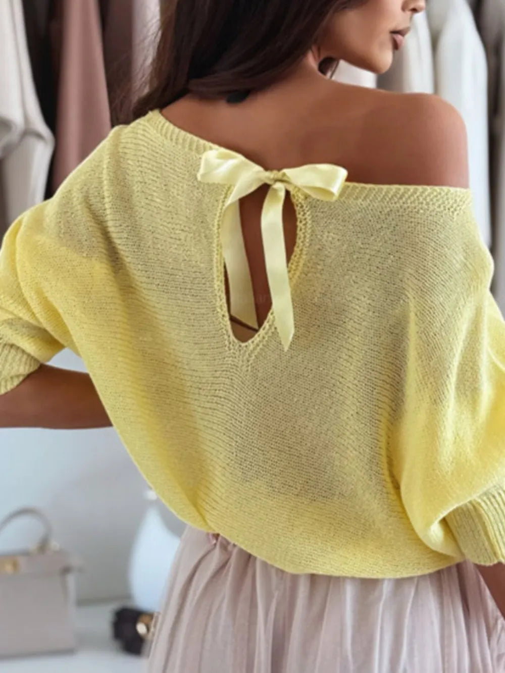 Stunning bow tie back detail on women’s off-shoulder lightweight knit sweater

Yellow off-shoulder top with a bow detail on a blurred background