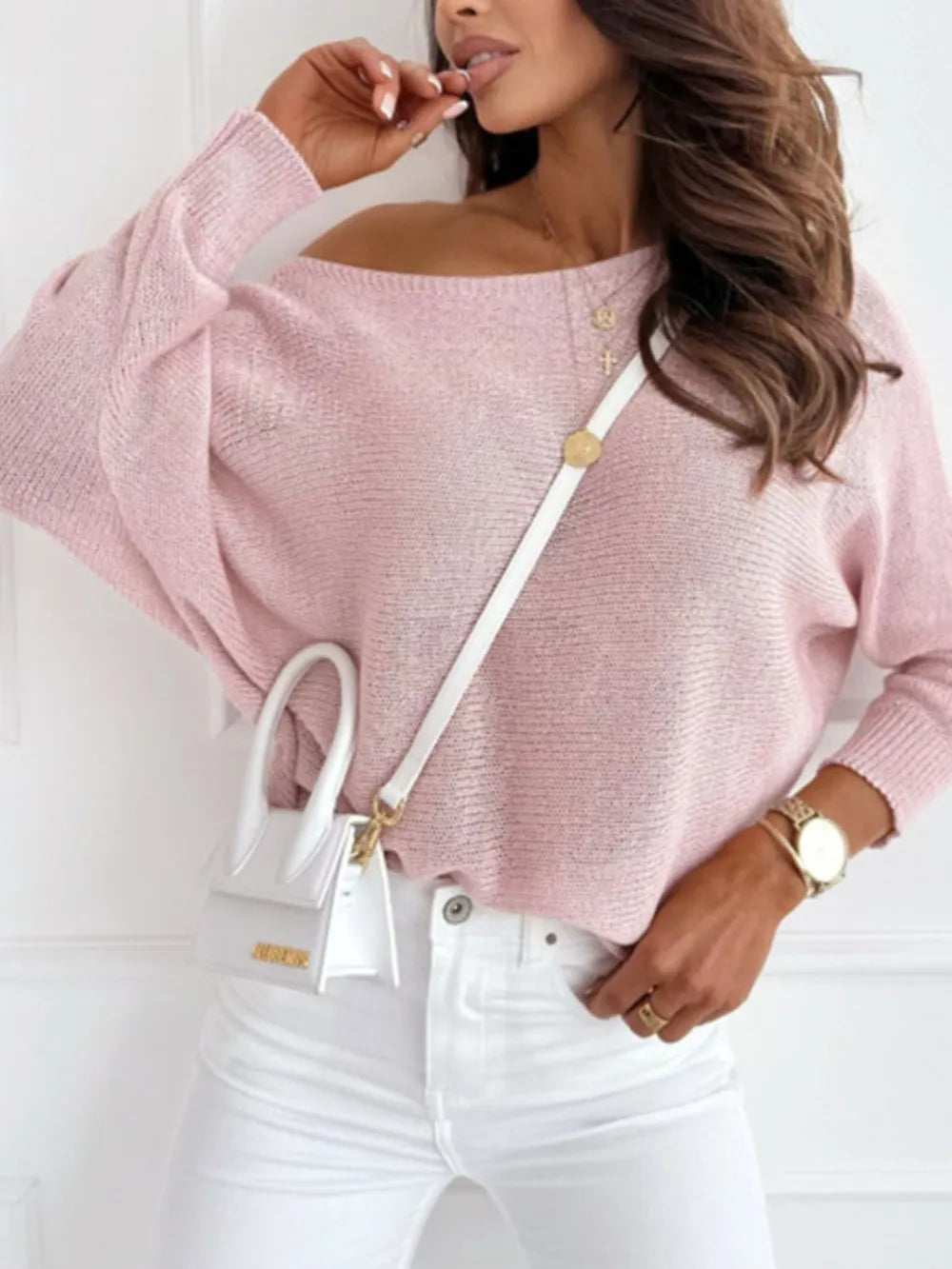 Side view showing draped off-shoulder neckline and bow back detail

Woman wearing a pink sweater and white pants with a white handbag.