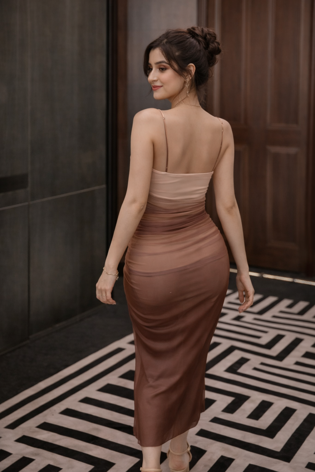 ombre-bodycon-dress-gradient-closeup
Close-up of seamless nude-to-cocoa ombré gradient and precision ruching on sheer midi dress
Woman in a brown dress standing in a room with a geometric patterned floor.