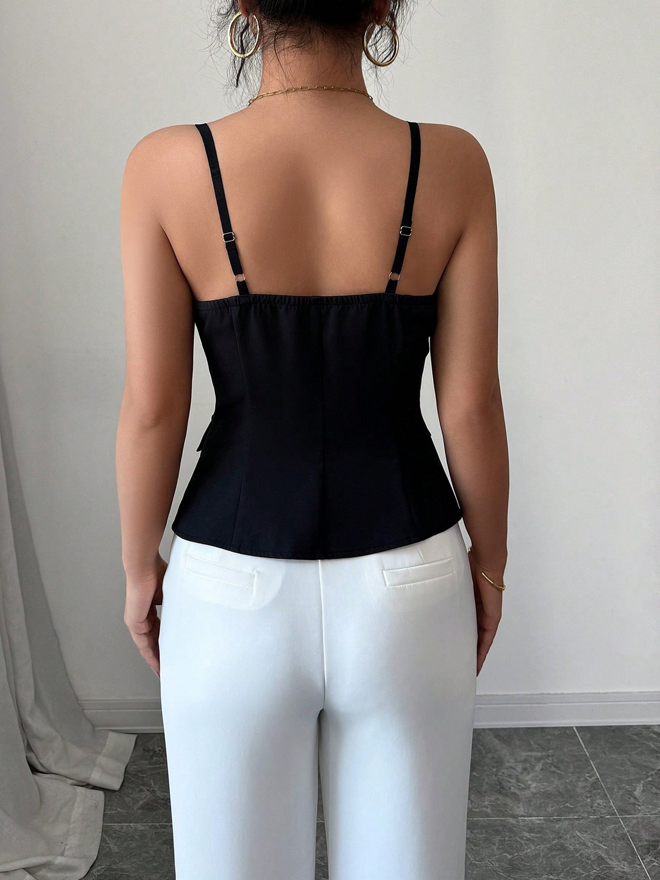 Women's black fitted cami top with adjustable spaghetti straps and a straight back design, back view.