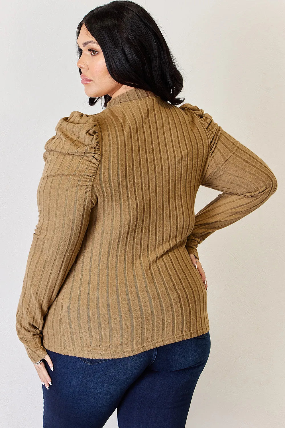 Woman wearing a brown ribbed sweater and blue jeans against a plain background

ribbed-mock-neck-top-winter-tuck
Winter styling: ribbed ruched top half-tucked into jeans with coat

