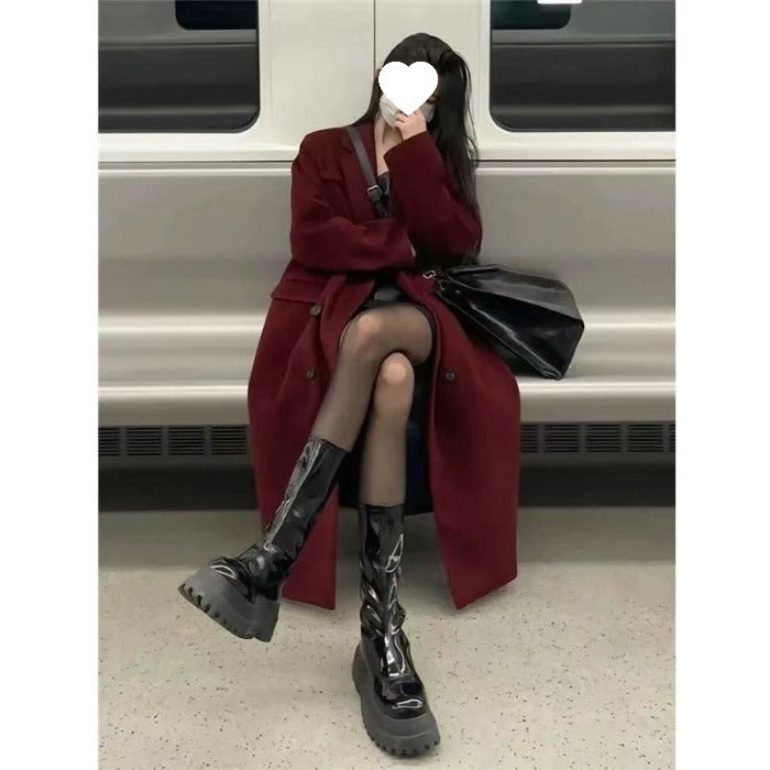 wine-red-trench-coat-pockets-detail
Close-up of functional side pockets and rich wine red fabric on elegant women’s winter trench coat
Person wearing a long red coat and black boots sitting on a train bench.